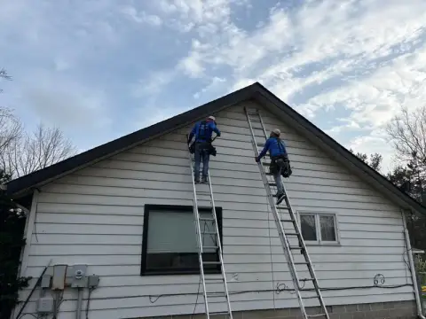 Homes Roofing crew working on the fascia along a roof edge